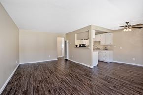 Orange apartment for rent - an empty living room and kitchen with a ceiling fan
