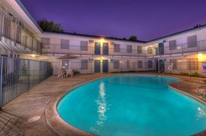 Orange apartment for rent - the swimming pool at night at an apartment building with a blue pool