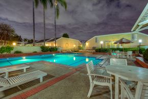 Fullerton apartment for rent - a swimming pool with tables and chairs around it at night