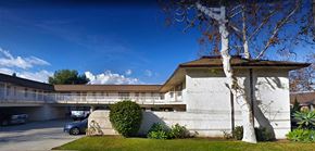 Santa Ana apartment for rent - a white building with a tree and a parking lot