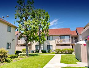 Garden Grove apartment for rent - an apartment building with a yard and a tree in front of it