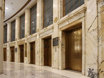 Expansive restored lobby with exquisite marble floors and elevator facade, fountain and gold leaf details