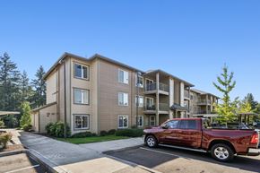 Happy Valley apartment for rent - A red pickup truck is parked in a parking lot in front of a building.