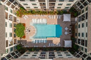 Brentwood apartment for rent - A swimming pool surrounded by lounge chairs and trees in a courtyard.
