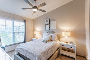 Brentwood apartment for rent - A bedroom with a large bed, a ceiling fan, and two lamps.