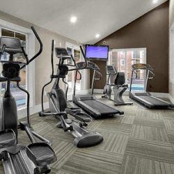 Littleton apartment for rent - a gym with cardio equipment and a tv on the wall