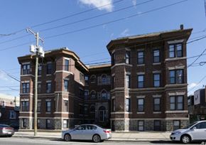 Philadelphia apartment for rent - A large brick building with a car parked in front.