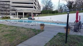 Nashville apartment for rent - a swimming pool with chairs and umbrellas in front of a building