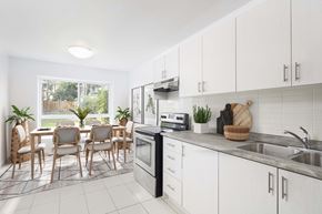 Toronto apartment for rent - Kitchen with white cabinets overlooking a dining room staged with furniture