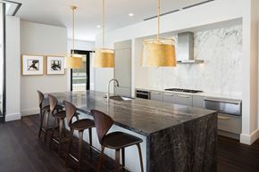 Dallas apartment for rent - the kitchen has a large marble island with seating and three hanging lights