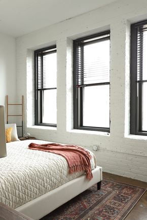 Milwaukee apartment for rent - A bedroom with a bed, pillow, and a blanket with a window in the background.