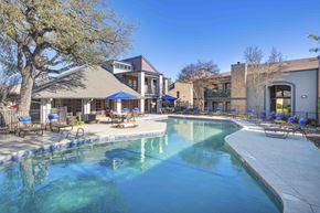 Austin apartment for rent - A large swimming pool surrounded by a patio with chairs and umbrellas.