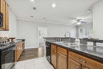 Round Rock apartment for rent - A kitchen with black appliances and wooden cabinets.