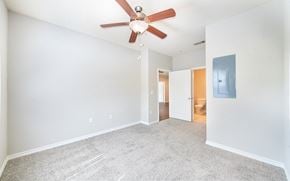 Round Rock apartment for rent - an empty living room with a ceiling fan and a door to a bathroom