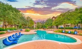 Round Rock apartment for rent - a swimming pool with blue lounge chairs at sunset