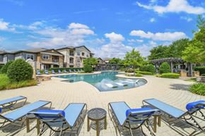 Austin apartment for rent - A pool surrounded by blue lounge chairs and a clear sky.