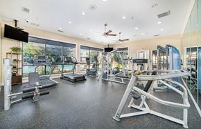 Fairview apartment for rent - a gym with cardio machines and weights on the floor and large windows