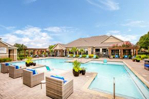 Carrollton apartment for rent - a swimming pool with chairs around it in front of a building