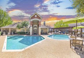 Round Rock apartment for rent - A large outdoor swimming pool with a building in the background.