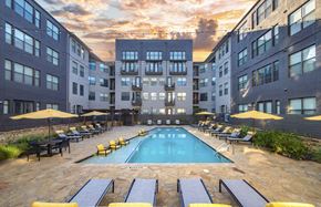 Dallas apartment for rent - a swimming pool in the middle of an apartment building with yellow umbrellas