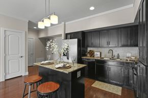 Mckinney apartment for rent - a kitchen with black cabinets and a table with stools