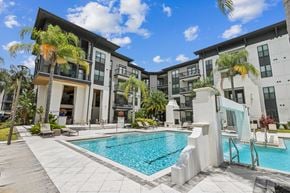 Jacksonville apartment for rent - A swimming pool is surrounded by a white concrete patio and a white staircase.