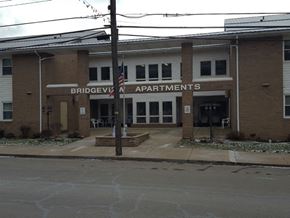 Emlenton apartment for rent - The front of the Bridgeview Apartments building with a sign and an American flag.