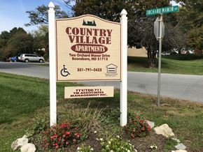 Boonsboro apartment for rent - A sign for Country Village Apartment is displayed in front of a street sign.