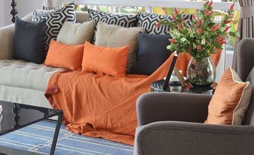Harrison City apartment for rent - A living room with a grey couch, orange pillows, and a grey armchair.