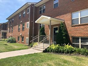 Martinsburg apartment for rent - A brick building with a white awning and a small tree in front.