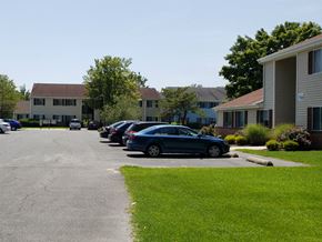 Pocomoke apartment for rent - A parking lot with cars and apartment buildings in the background.