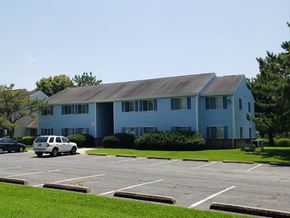 Pocomoke apartment for rent - A white car is parked in a parking lot in front of a blue building.