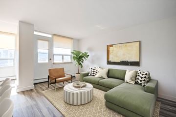 Hamilton apartment for rent - A living room with a green couch, a brown chair, and a large painting on the wall.