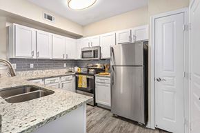 Mckinney apartment for rent - A kitchen with a stainless steel refrigerator and a granite countertop.