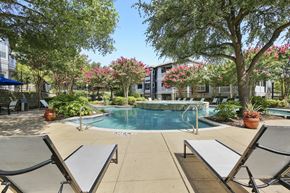 Mckinney apartment for rent - a swimming pool with lounge chairs and trees with apartments in the background