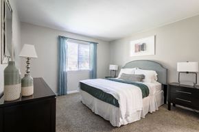 Aurora apartment for rent - Aurora, CO Apartments - Copper Flats - Bedroom with Plush Carpet Flooring, Bed, Nightstands with Lamps, Dresser, and Window.