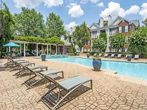 Atlanta apartment for rent - a swimming pool with chairs and a building in the background