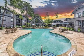 Houston apartment for rent - a swimming pool with a sunset in the background at an apartment complex