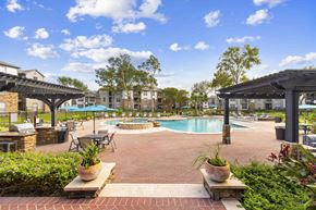 Houston apartment for rent - A pool area with a table and chairs and umbrellas.