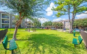 Houston apartment for rent - a park with benches and trees in front of houses