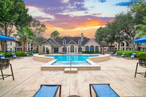 Houston apartment for rent - a swimming pool with chairs and a house in the background
