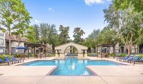 Houston apartment for rent - a resort style pool with lounge chairs around it and trees