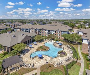 Cypress apartment for rent - A large swimming pool surrounded by a grassy area and apartment buildings.