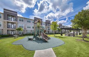 Houston apartment for rent - a playground with a slide in a park in front of an apartment building