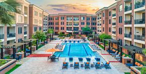 Houston apartment for rent - an outdoor pool with chairs and umbrellas at an apartment building