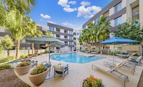 Scottsdale apartment for rent - a swimming pool with chairs and umbrellas in front of a building