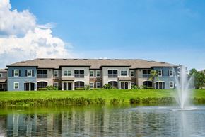 Tampa apartment for rent - an apartment building overlooking a lake with a fountain