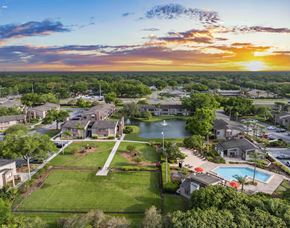 Tampa apartment for rent - an aerial view of a community with a pool and a lake at sunset