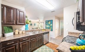 Heathrow apartment for rent - a kitchen with wooden cabinets and granite counter tops and a sink