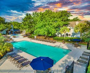 Charleston apartment for rent - a swimming pool with chairs and umbrellas and a building in the background
